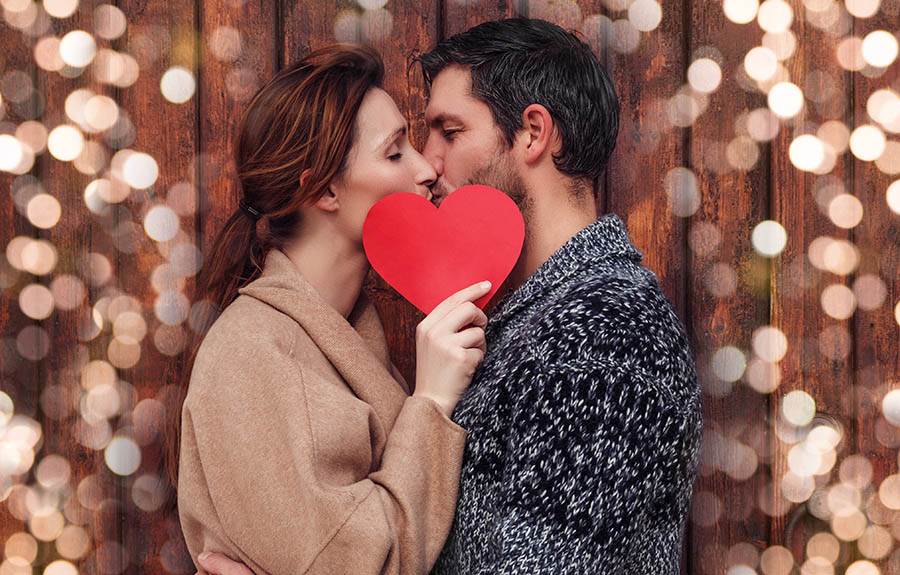 couple kissing with a paper heart